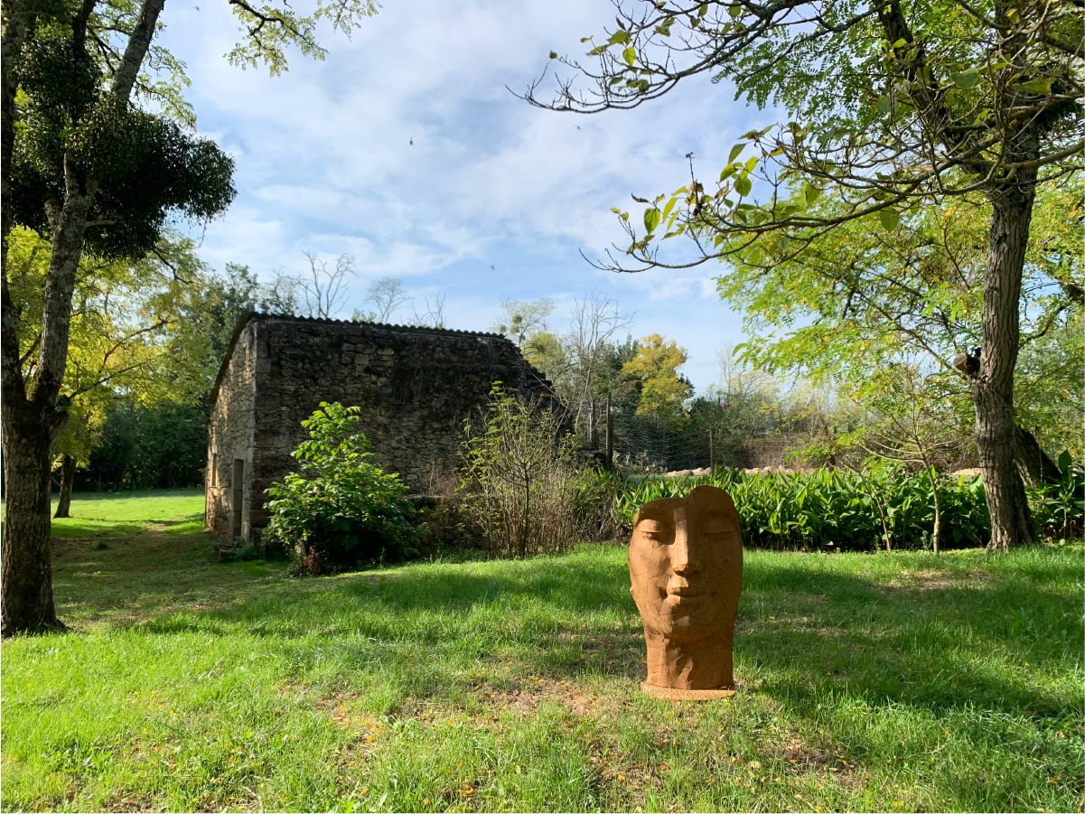 Sculpture de visage dans le jardin calme des gites de La Petite Toscane à mauriac, gironde