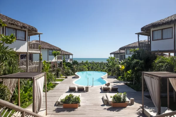Yemanja pool framed by thatched-roof bungalows, with open ocean view