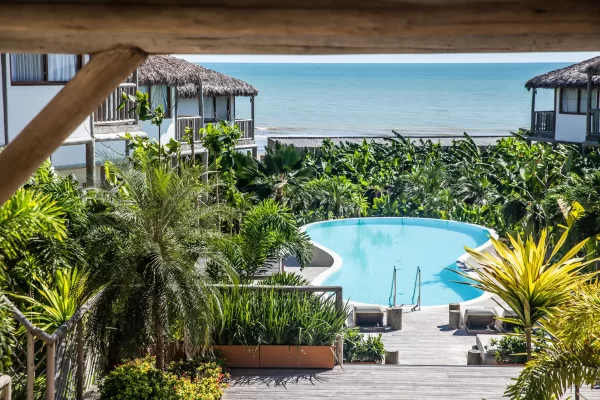 View from a wooden pergola over the Yemanja pool and bungalows, surrounded by palm trees