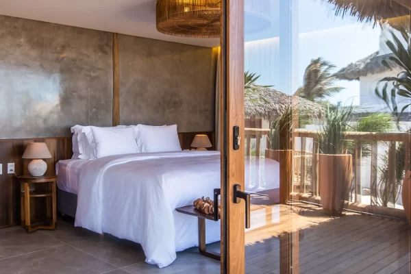 King size bedroom with white linen and sliding door opening onto a tropical balcony with palm trees