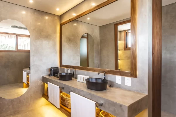 Bathroom with double black basin, concrete vanity top, large wooden mirror and warm ambient lighting